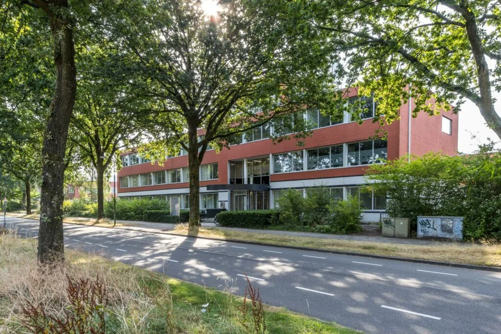 Appartementencomplex aan de Jan van Eycklaan met rode gevel, omringd door bomen en groenstroken.